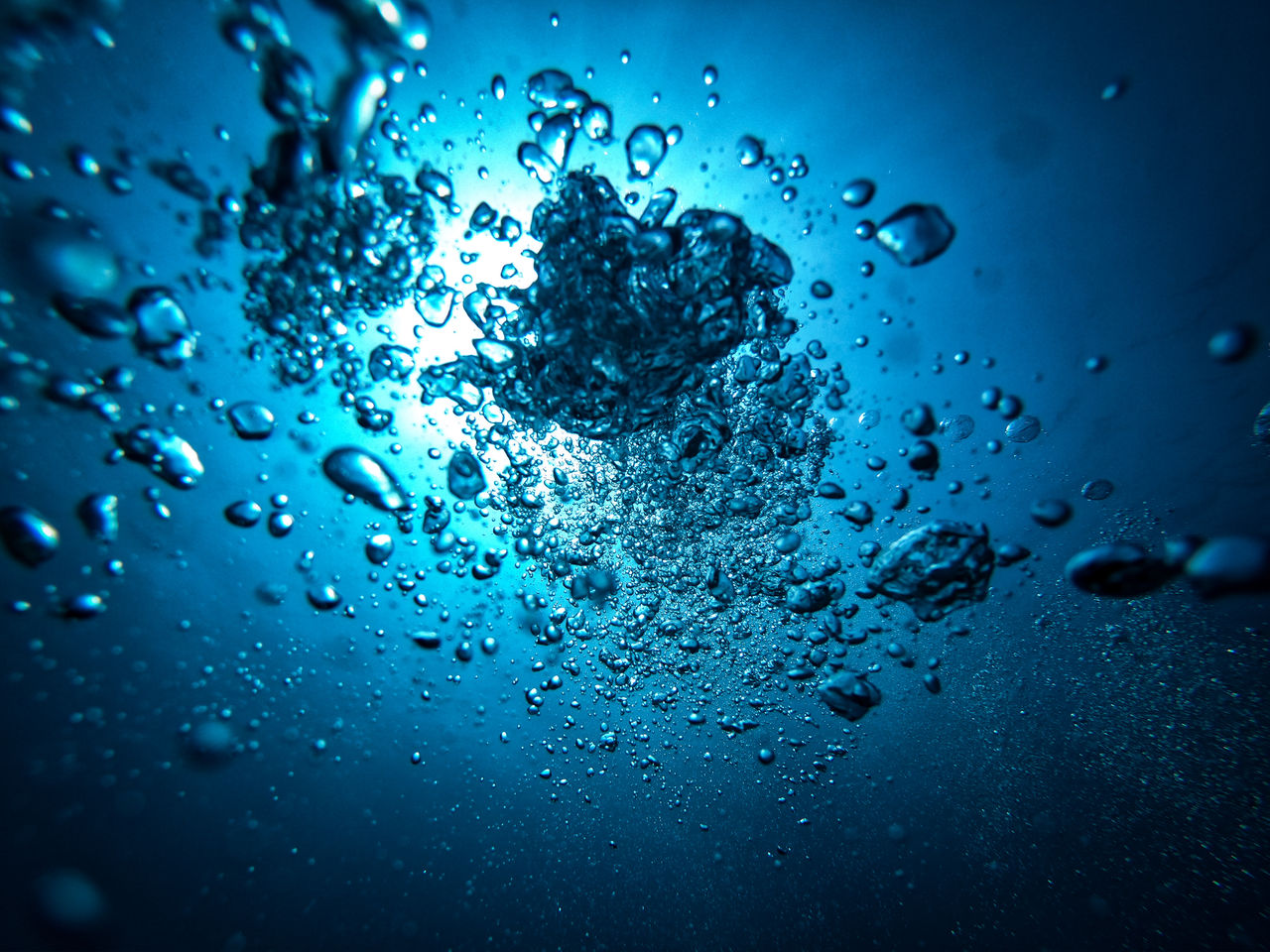 Underwater bubbles rising toward sunlit surface