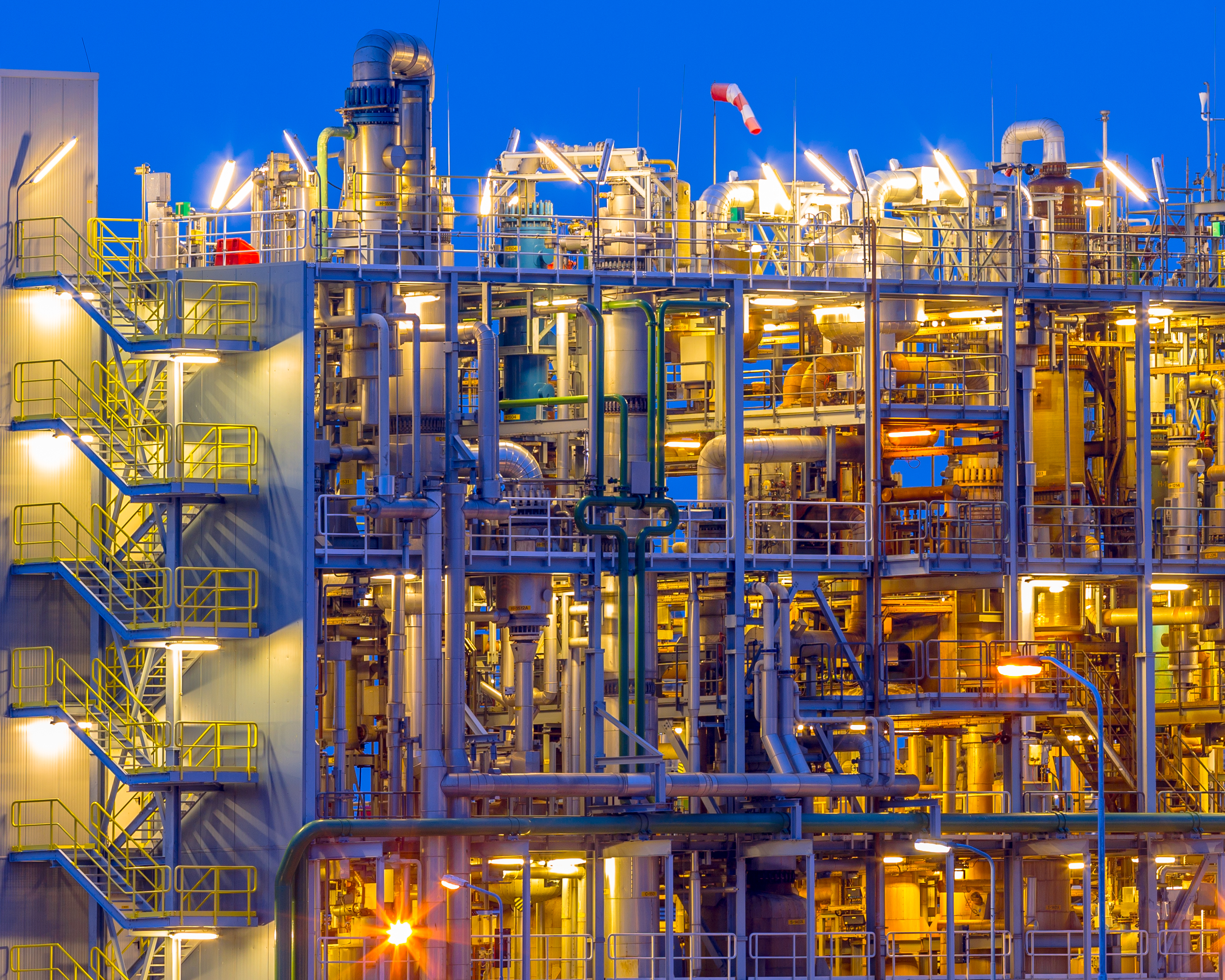 Industrial refinery plant illuminated at dusk with staircases