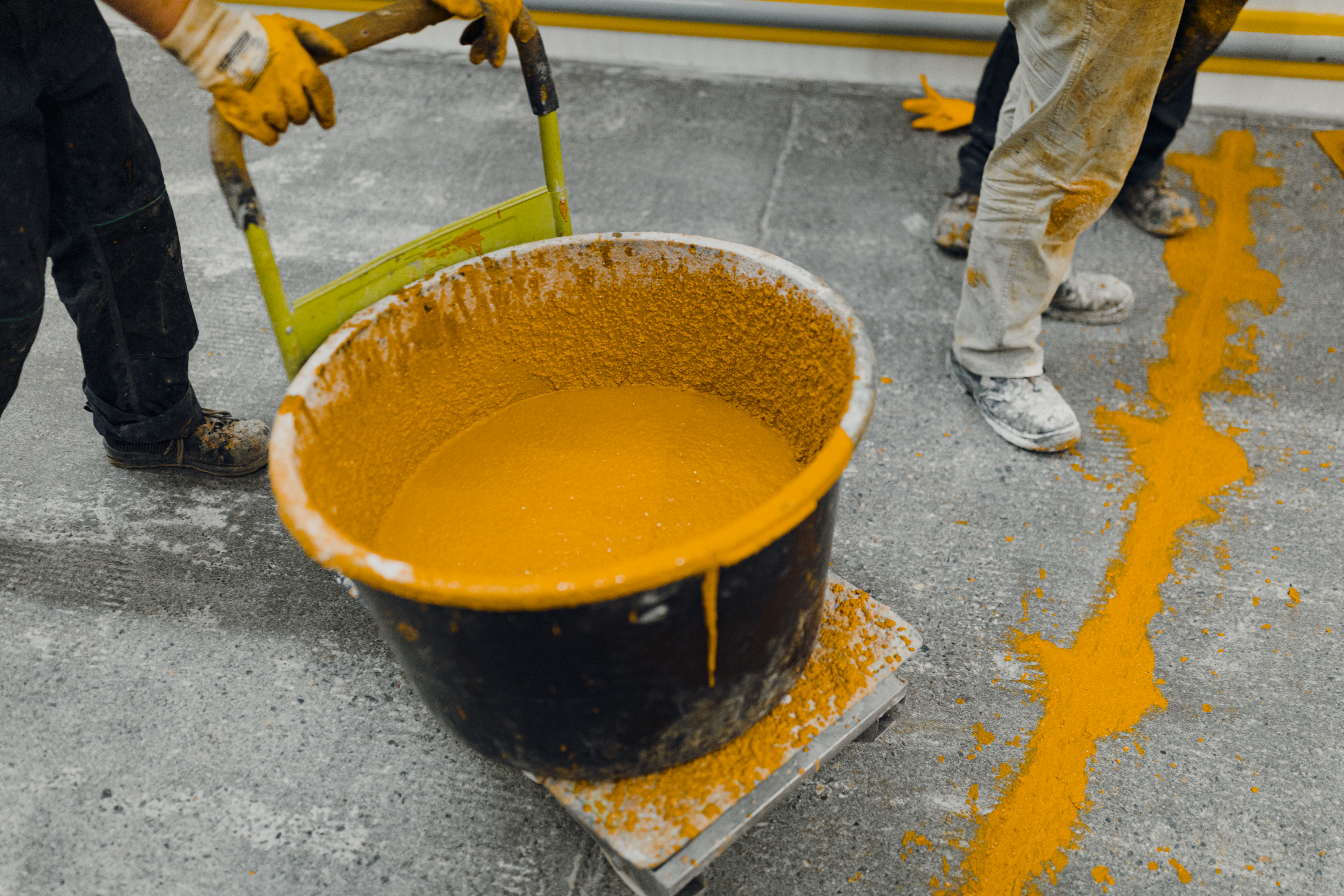 A large bucket of yellow paint being transferred