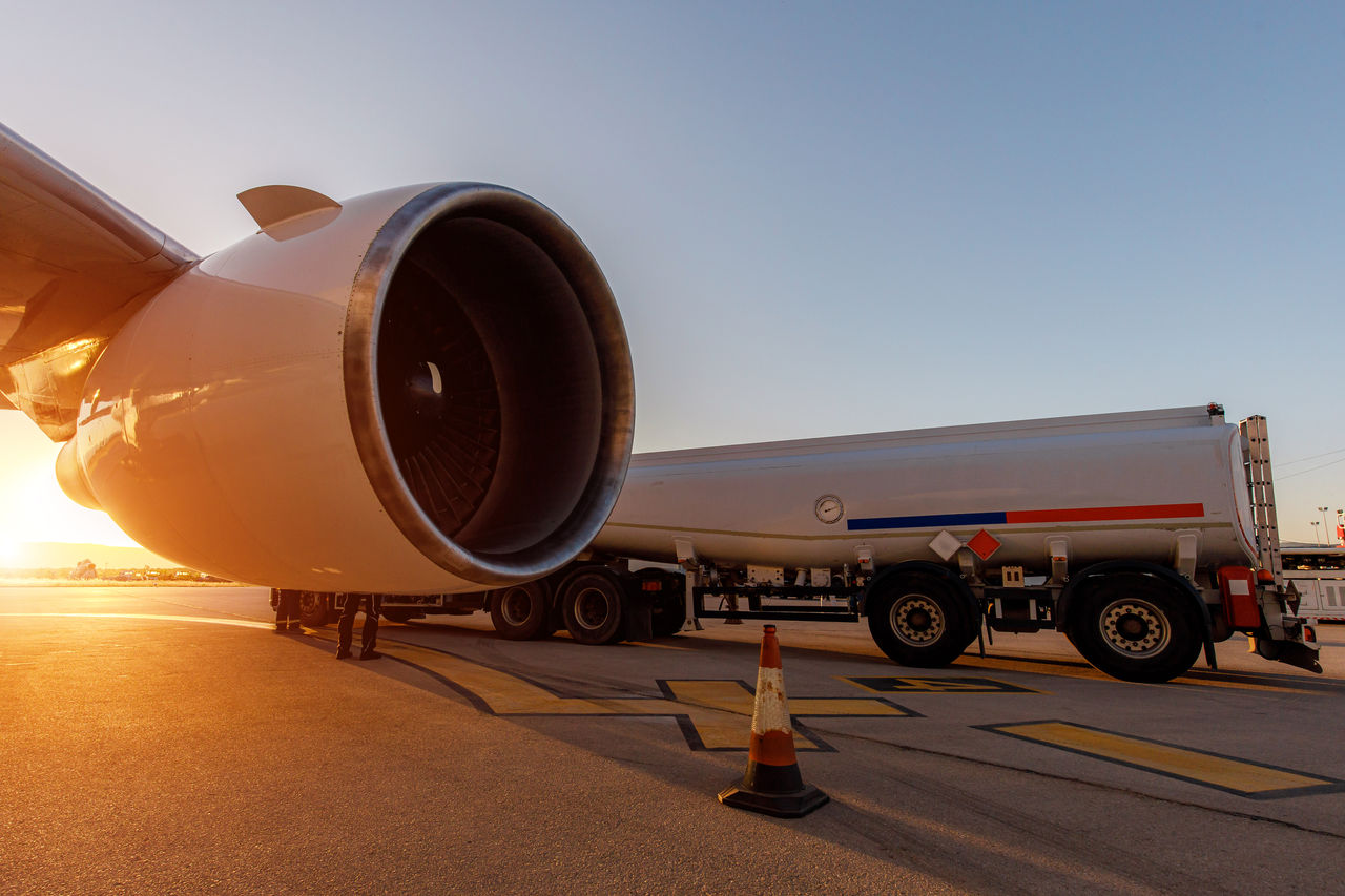 Jet engine and fuel tanker at airport during sunrise