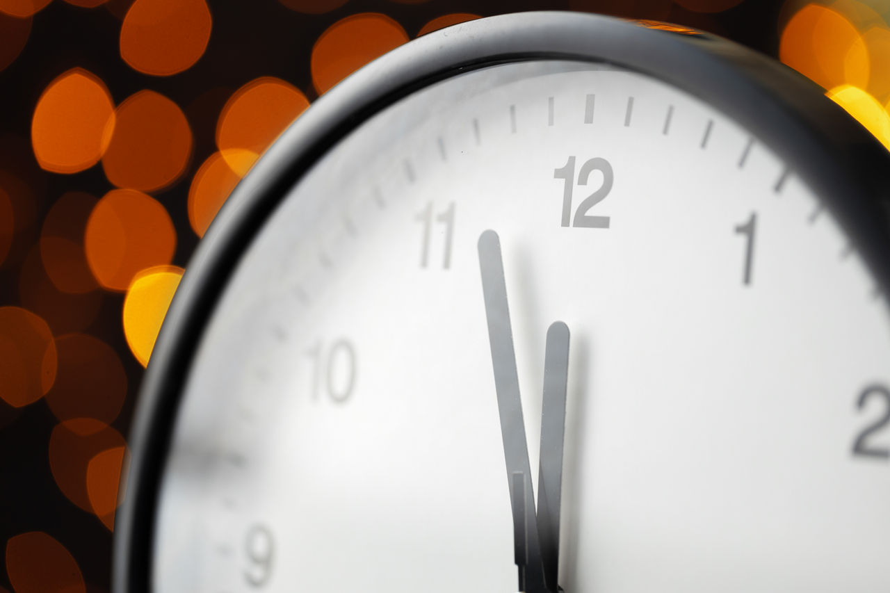 Close-up of clock striking midnight with lights