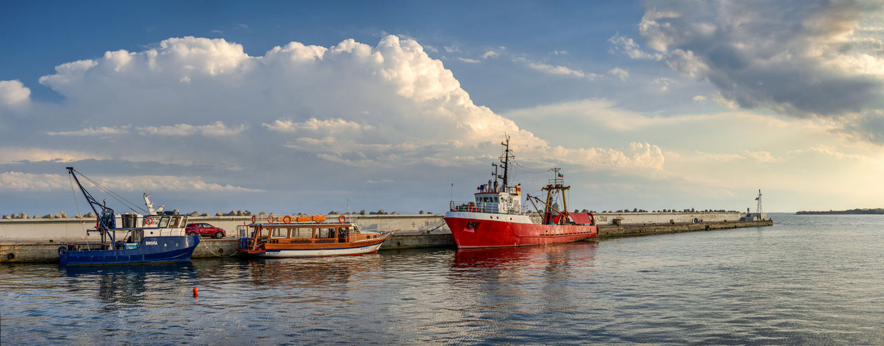 Colorful fishing boats docked at harbor under clouds