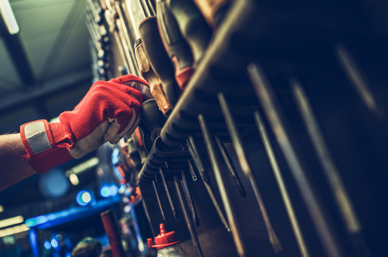 Worker selecting tool from organized workshop wall